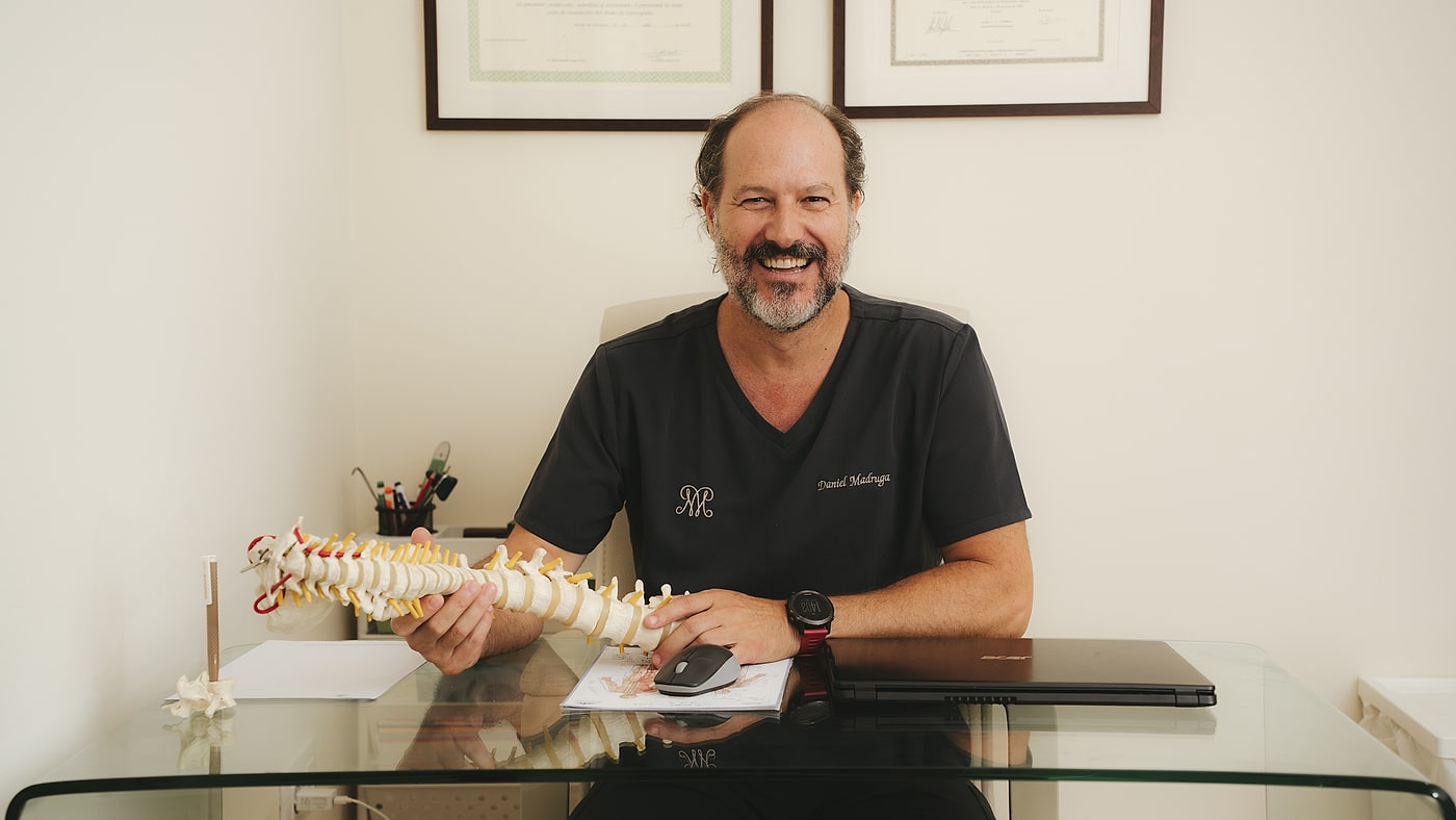 Fisioterapeuta de Montecarlo International Clinic en su consulta de Sevilla, con un modelo de columna vertebral